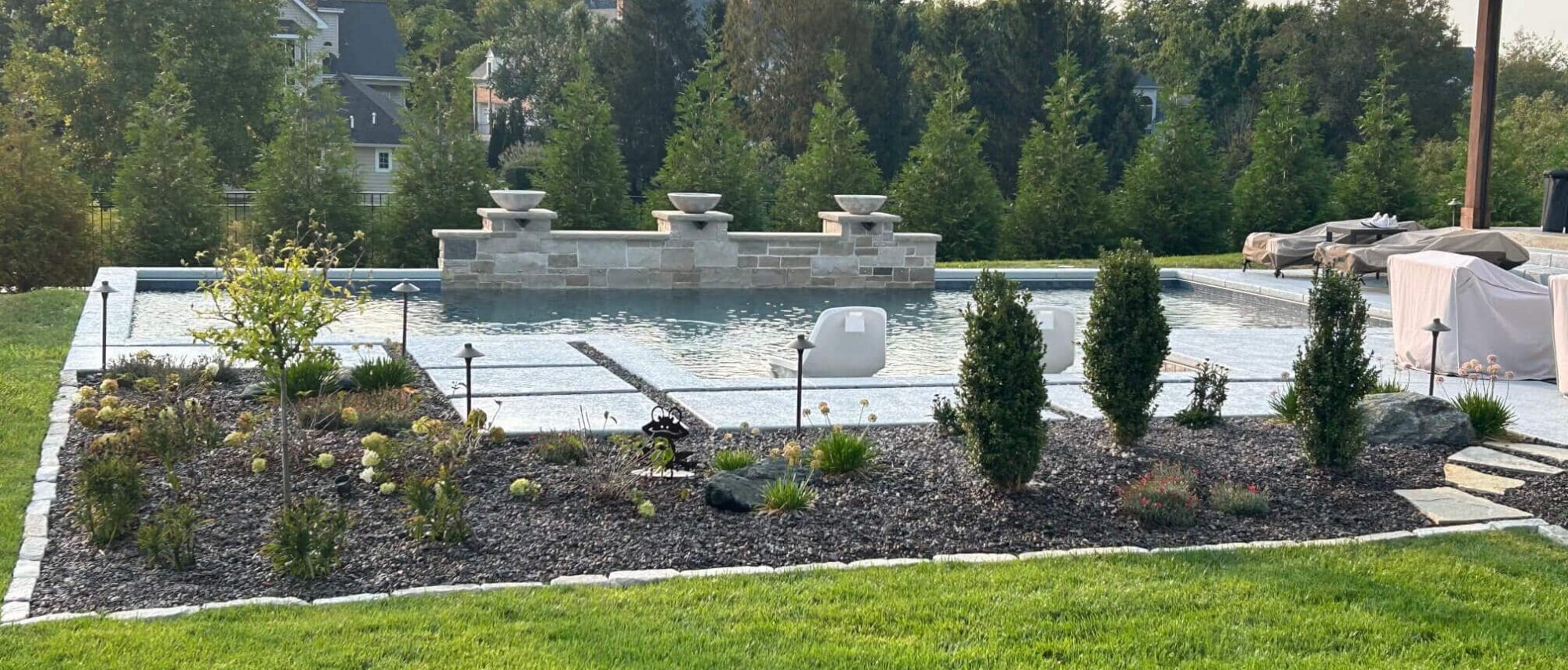 Outdoor swimming pool surrounded by retaining wall and new landscaping