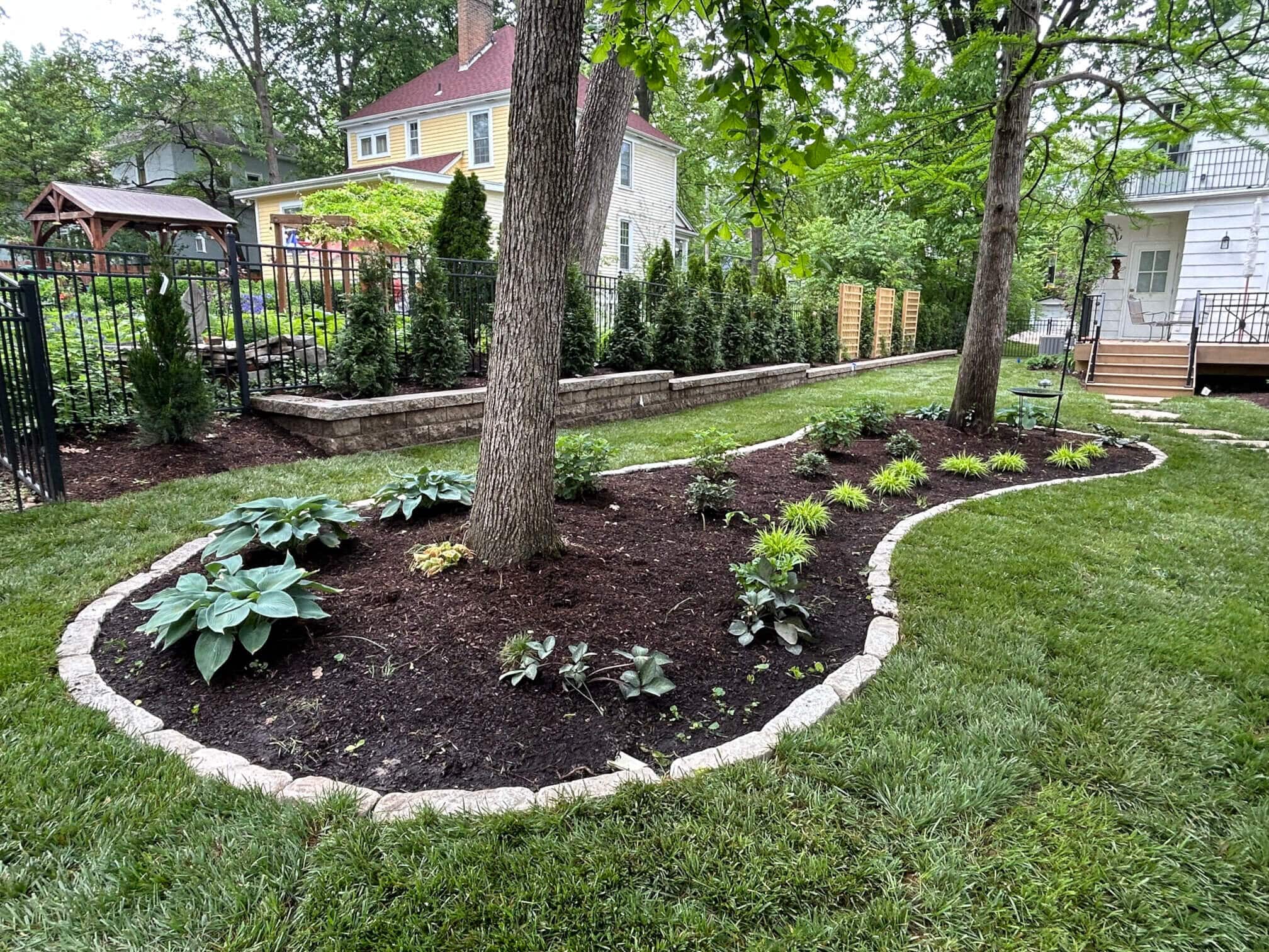 Updated landscaping with new plants and stone border with trees inside the border