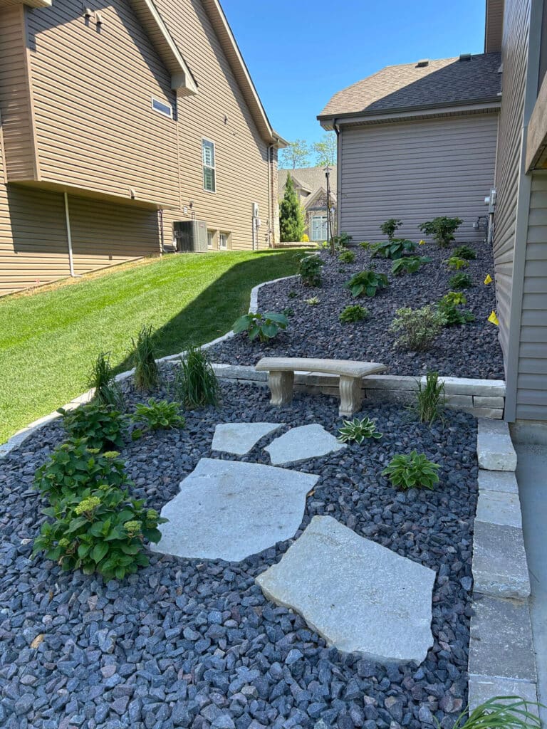 Decorative rock with hostas, shrubs, and a stone border